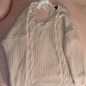 A light cream, knit sweater with white bow